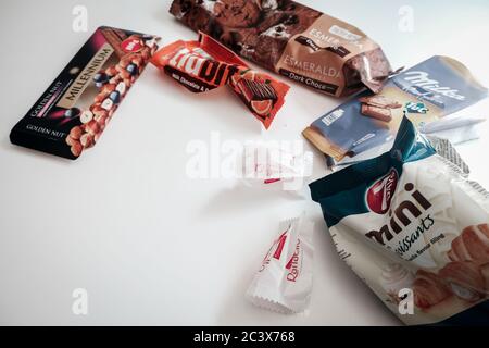 Lviv / Ukraine - April 2020: Assorted candy, cookie and chocolate wrappers left on a white table. Delicious sweets full of sugar Stock Photo