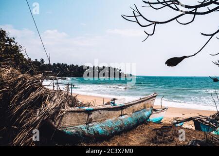 Abandoned old fishing boat on the beach. Deserted landscape on an isolated island. Forgotten and lonely near the seashore. Neglected seaside Stock Photo