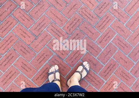 Portland, Oregon, USA - April 27, 2018 : Woman legs standing on the floor red bricks with engraving names at Pioneer Courthouse Square in Portland Stock Photo