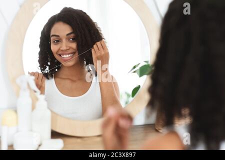 Oral Hygiene. Beautiful african american girl using dental floss at home Stock Photo
