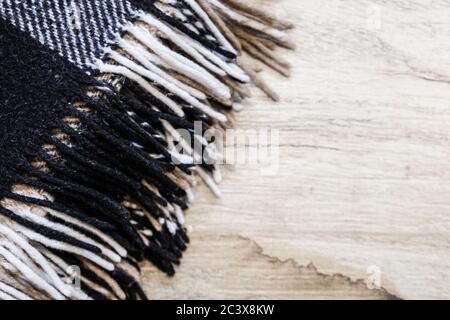 Brown plaid blanket with long edges. Close up view on a laminate surface. Textile in interior design. Warming up cozy material to cover up when study Stock Photo