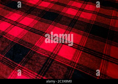 Bright red geometric background texture. Warm red and black pattern. Wrinkled shirt surface at home. Close up winter wrap for coziness. Soft material Stock Photo