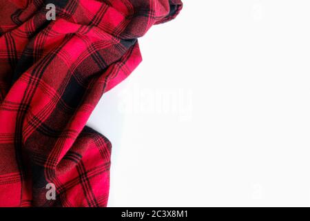 Bright red plaid wrinkled shirt on a white background. Environment for working or studying from home. Empty surface surrounded by soft warm material. Stock Photo