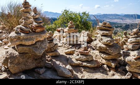 Stacked stones close up from Ronda, Spain. Spiritual piles of rocks (cairn) for calmness and meditation. Mountains in the background at a tourist spot Stock Photo