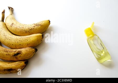 Close up view of a yellow bananas row and a bottle of hand sanitizer on a white desk. Healthy diet for good immunity and covid-19 virus spreading Stock Photo