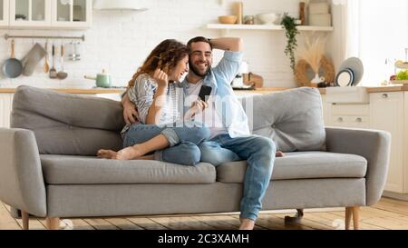 Smiling man and woman hugging using smartphone reading joke. Stock Photo