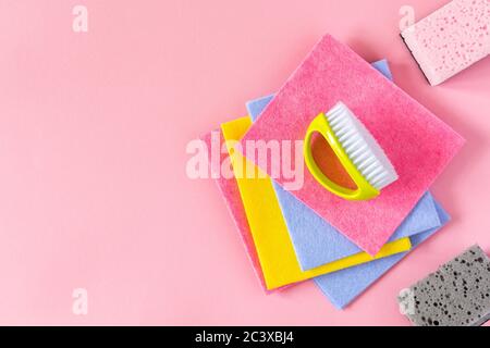 Multi-colored cloths and cleaning sponges on pink background Stock Photo
