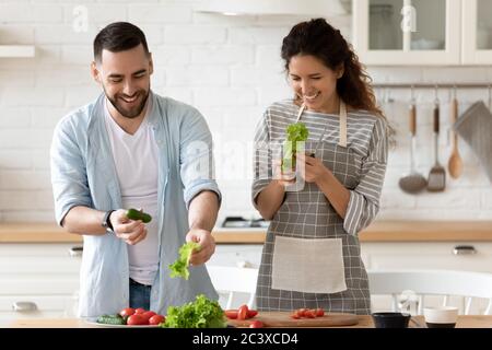Happy couple laughing holding green cucumber in hands. Stock Photo