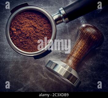 Fresh ground coffee in a coffee horn and temper on a dark background, accessories for making coffee, stylized Stock Photo