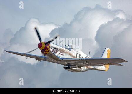 A World War II-era P-51 Mustang fighter airplane flies through storm clouds. Stock Photo