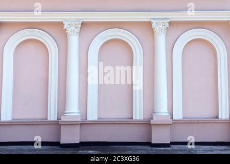 Pink windowless facade of the building with white columns and arches. Beautiful exterior. Background, wallpaper Stock Photo