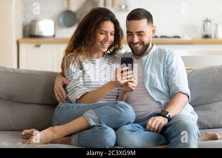 Close up smiling man and woman hugging using smartphone. Stock Photo