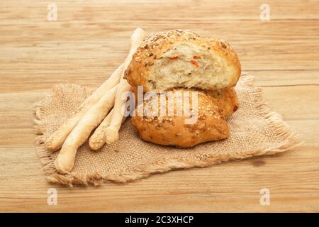Two buns with sesame seeds and bread sticks lie on the sacking on the background of a tree Stock Photo