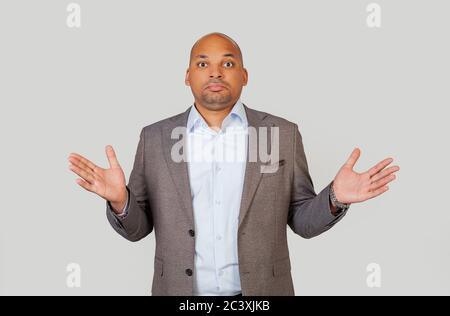 Puzzled embarrassed, black African-American young man, shrugging his shoulders in frustration with a completely lost and bewildered look, I do not know the answer to the question. Language of the body Stock Photo