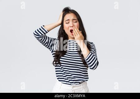 Lifestyle, people emotions and casual concept. Sleepy tired woman working late in office, close eyes and yawning, want go bad. Asian girl woke up Stock Photo
