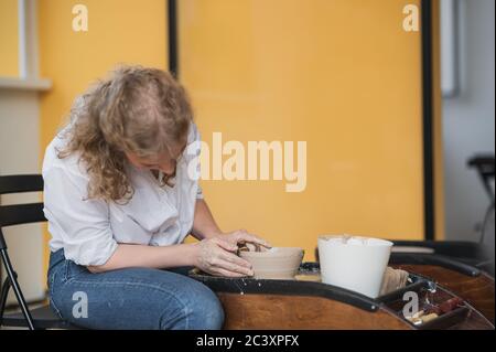 Potter makes the clay product with pottery modeling tools on the potter's wheel. Stock Photo