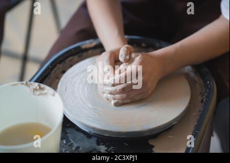 The manufacture of ceramics. Woman prepare clay for work on pottery wheel. Close up view of hands. Stock Photo