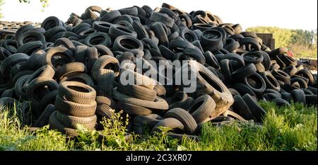 Large pile of used old, black tires at sunset Stock Photo