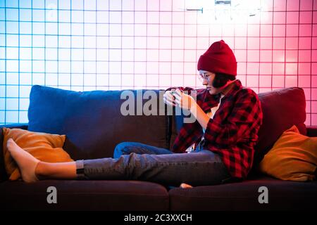 Woman sit on sofa and play mobile game happily at home Stock Photo