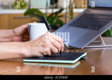Female designer hands using a drawing graphics tablet and a laptop while working at home Stock Photo