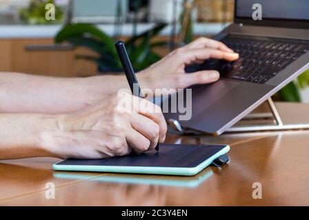 Female designer hands using a drawing graphics tablet and a laptop while working at home Stock Photo
