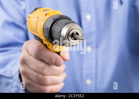 extreme closeup of a man holding an electric drill with a screwdriver bit Stock Photo