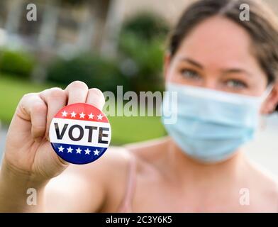 Portrait of women wearing face mask holding Vote button Stock Photo