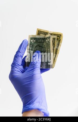 Studio shot of hand in latex glove holding folded dollar bills Stock Photo