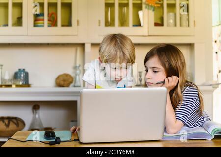 Boy (4-5) and girl (6-7) looking at laptop at home Stock Photo