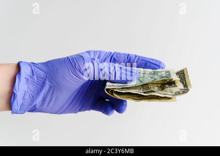 Studio shot of hand in latex glove holding folded dollar bills Stock Photo