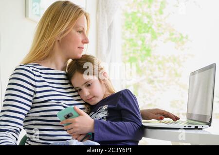 Mother working on laptop while daughter (6-7) using smart phone Stock Photo