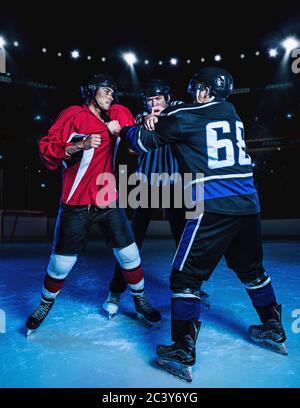 Referee separating fighting hockey players Stock Photo