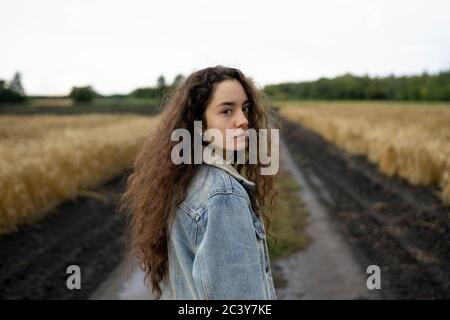 Russia, Omsk, Portrait of young woman with brown hair standing in field Stock Photo