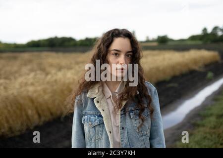 Russia, Omsk, Portrait of young woman with brown hair standing in field Stock Photo