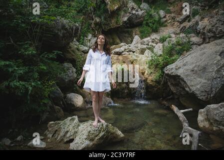 Ukraine, Crimea, Young woman standing on rock near waterfall Stock Photo