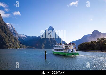 Milford Sound, Fiordland, New Zealand, June 20 2020:Tourists on board a cruise boat heading out into Milford Sound with Mitre Peak in the distance Stock Photo