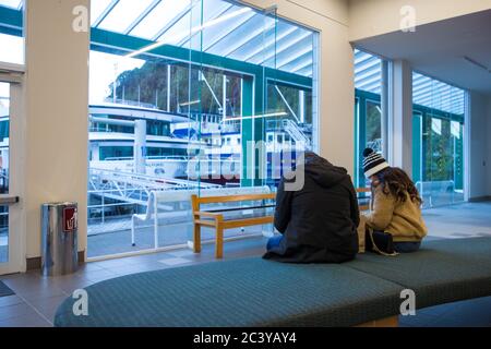 Milford Sound, Fiordland, New Zealand, June 19 2020: Two New Zealand tourists in the ferry terminal at Milford Sound, waiting to go on a cruise Stock Photo