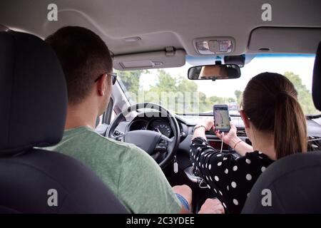 Young couple driving in car and using mobile navigation Stock Photo