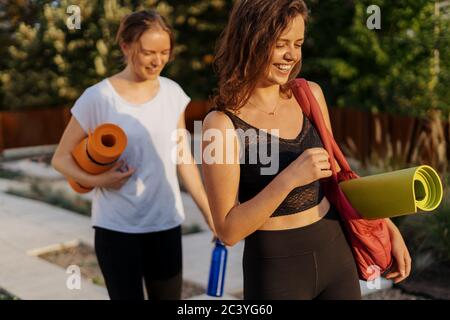 Two young beautiful women in sportswear going to do sports training, gymnastics, yoga. Healthy sports lifestyle concept. Women friendship Stock Photo