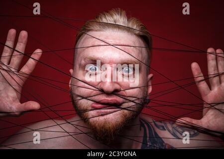 Photo of tangled in black threads scared man Stock Photo