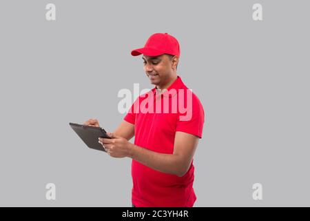 Delivery Man Using Tablet. Indian Delivery Boy with Tablet. Home Delivery Technology Stock Photo
