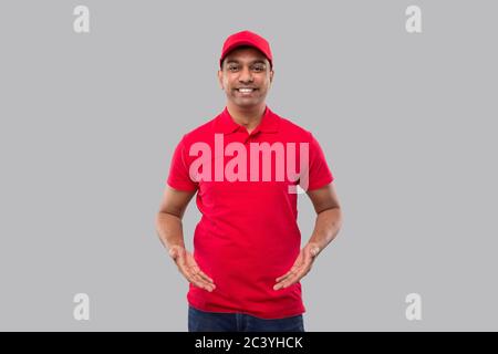 Delivery man Holding Empty Open Hands in front of Chest Isolated. Indian Delivery boy Advertisment Concept Stock Photo
