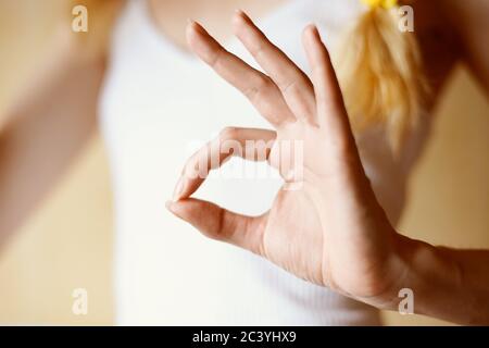 Female hand shows ok sign on the background of the young body in a white T-shirt Stock Photo