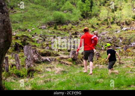 Mother with toddler on arm followed by son exploring the rough country side surrounding the 'Steirischer Bodensee', Schladming region, Styria, Austria Stock Photo