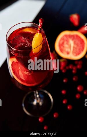 Glass of aperol spritz cocktail with grapefruit and strawberries on wooden table in cafe Stock Photo
