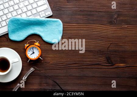 Hard exhausing work concept. Sleep mask on wooden office desk top view copyspace Stock Photo