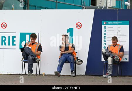 leiden, netherlands - 2020.06.16 tu:  three construction workers sitting outside their construction site during a break at vismarkt in the city centre Stock Photo