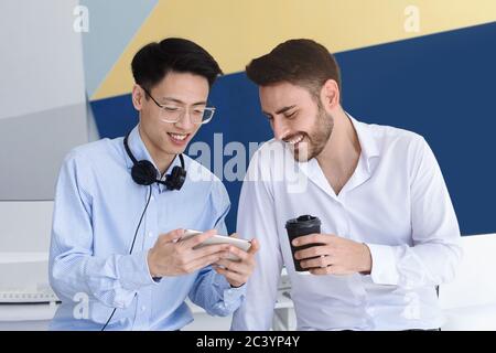Male customer support operators with coffee and smartphone having break at call center office Stock Photo