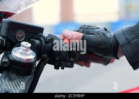 biker puts his hand on the gas handle on the motorcycle, turns on the ignition Stock Photo