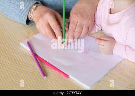 Grandmother teaches little granddaughter to draw Stock Photo